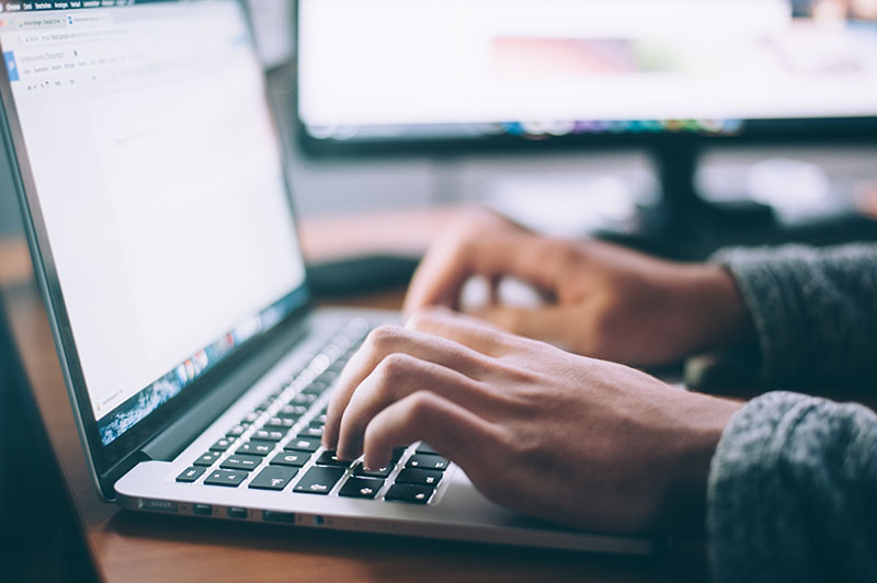 A game developer typing a cover letter on a laptop